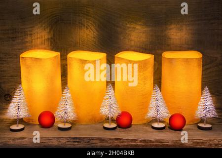 4 golden electric LED wax candles and Christmas decoration on wooden background Stock Photo