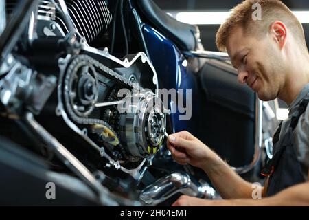 Master repairing motorcycle in workshop using wrench Stock Photo