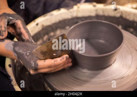Womens hands at work on a potters wheel with black clay blank Stock Photo