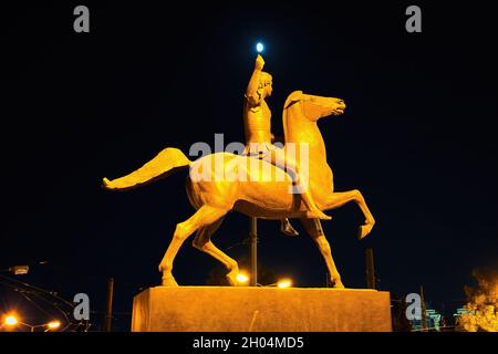 ATHENS, GREECE - Sep 16, 2021: Greece, Athens, a low angle shot of Alexander the Great statue at night, seems to catch the moon, under the street ligh Stock Photo