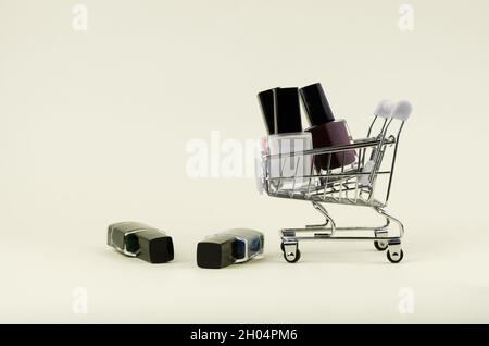 Different colors nail polishes in a shopping trolley on a beige background. beauty and fashion trendy concept. flat lay, top view Stock Photo