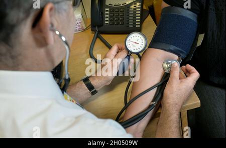 File photo dated 10/09/14 of a GP checking a patient's blood pressure. Patients are facing a 'postcode lottery' over seeing a GP in England, with the worst-affected areas served by half the number of doctors as the best. New analysis has shown that there is on average one GP per 2,038 people across the country, a 5% rise since 2015. Issue date: Monday October 11, 2021. Stock Photo