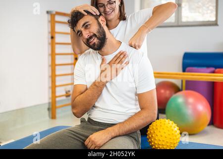 Woman Physical Therapist Stretching the Injured Neck of a Male Patient. Stock Photo