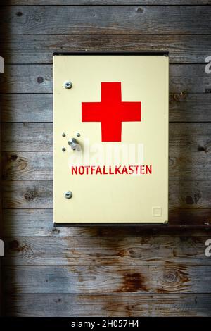 First aid kit with German label emergency kit hangs on wall of raw textured wood planks Stock Photo