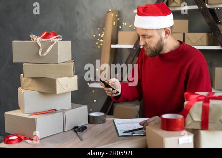 Small business owner entrepreneur works in the New Year's home office with boxes makes a photo on the phone with barcodes for clients. Online store Stock Photo