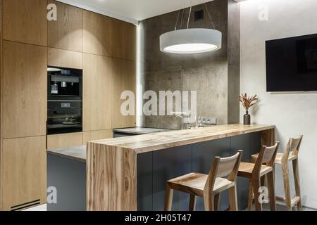 Modern minimalist kitchen interior with natural veneer wooden furniture, built-in equipment in a studio apartments. Interior design concept Stock Photo