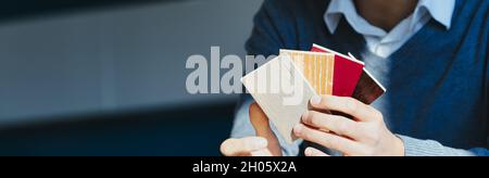 Panorama banner with male hand holding wood samples for decor fanned to show the choices over a dark background with copyspace Stock Photo