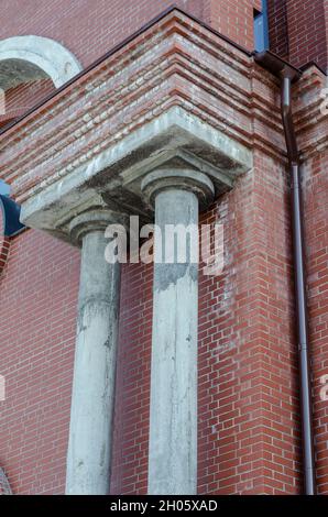 Red brick building with two gray columns. Concrete columns. Drainpipe. Construction Industry. Architecture. View from bottom to top. Stock Photo