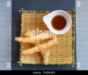 Shrimps tempura with soy sauce on yellow bamboo plate. Seafood tempura dish of traditional asian cuisine Stock Photo
