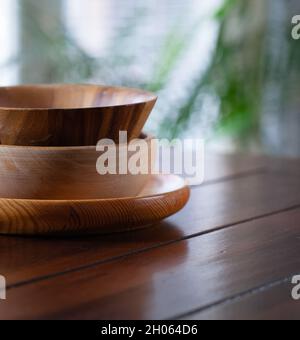 Three different kinds of wooden bowls stacked on wooden table. Stock Photo
