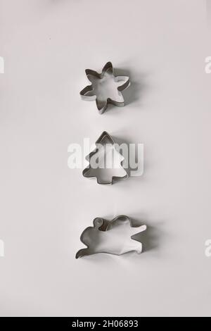 Christmas cookie cutters shot from above. Shapes of cutters Christmas tree, snowflake and rabbit Minimalistic composition, vertical Stock Photo