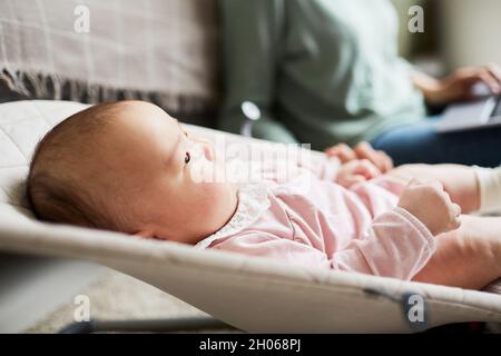Close-up of newborn girl lying on lounge chair and looking away in the room Stock Photo