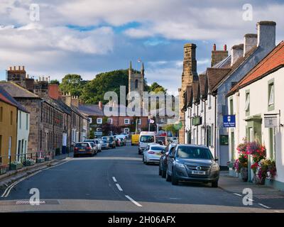 Sandstone buildings and the busy high street and church in the centre of Belford, an old, traditional English village in Northumberland, UK Stock Photo