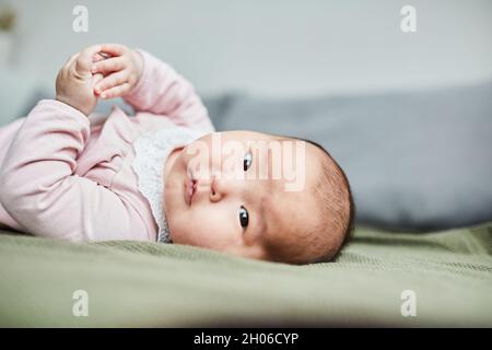 Close-up of Asian baby girl looking at camera while playing on the bed Stock Photo