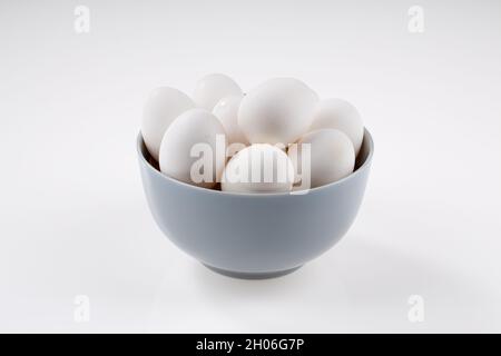 Chicken Egg,white eggs placed in a ceramic bowls with white textured background. Stock Photo