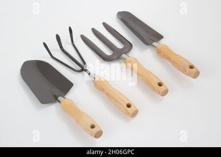 Small shovels and rakes with wooden handles, gardening tool isolated on white background Stock Photo