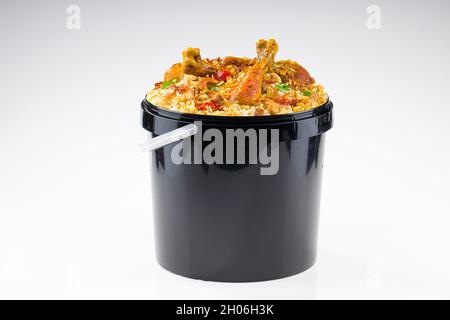 Chicken Bucket Biryani, Kerala dum chicken biryani arranged in a black bucket container with white textured background. Stock Photo