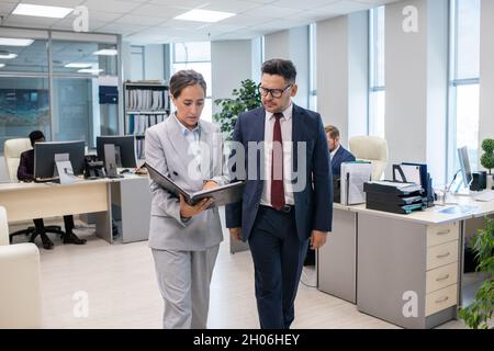 Two elegant employees discussing new contract held by businesswoman in suit Stock Photo