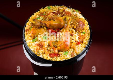 Chicken Bucket Biryani, Kerala dum chicken biryani arranged in a black bucket container with white textured background. Stock Photo