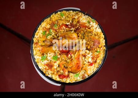 Chicken Bucket Biryani, Kerala dum chicken biryani arranged in a black bucket container with white textured background. Stock Photo