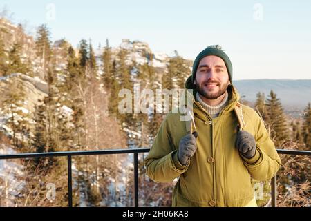 Young cheerful male traveler with backpack enjoying trip on winter weekend Stock Photo