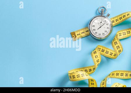 Fast workouts. Yellow measuring tape meter and stopwatch on a blue background. Template Copy space for text. Stock Photo
