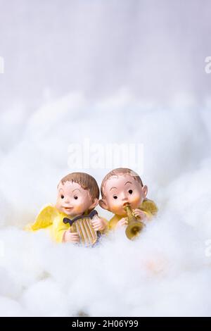 Two figures of angels on cotton simulating clouds. Christmas greeting concept. Copy Space