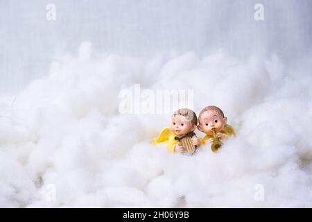 Two figures of angels on cotton simulating clouds. Christmas greeting concept. Copy Space