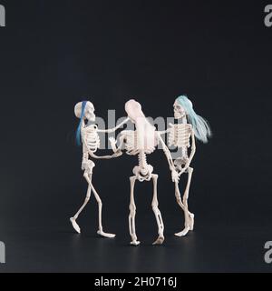 Three skeletons like three graces dancing on a black background. Square crop. Halloween motif with copy space Stock Photo