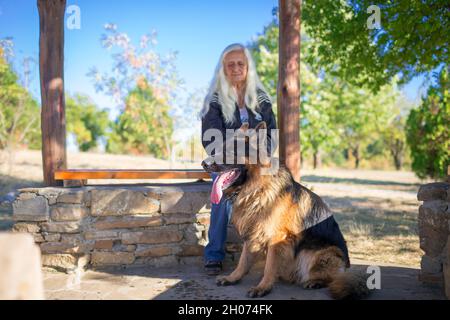 A woman takes a German Shepherd dog for a walk in nature Stock Photo