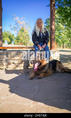 A woman takes a German Shepherd dog for a walk in nature Stock Photo