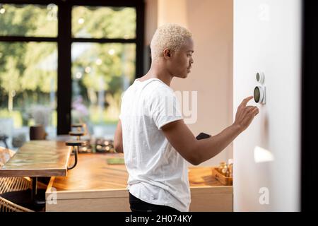Latin man choosing temperature on thermostat Stock Photo