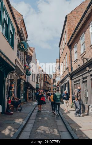 York, UK - June 22, 2021: People walk past shops on The Shambles, an old street in York, England, with overhanging timber-framed buildings, some datin Stock Photo