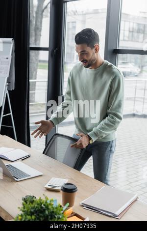 Happy arabian businessman having video call on laptop in office Stock Photo