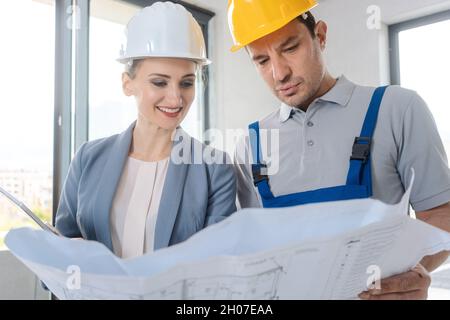 Construction worker and architect looking at plan on site Stock Photo
