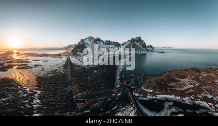 Aerial Drone scenic image of famous Stokksnes cape and Vestrahorn Mountain with colorful dramatic sky during sunset in Iceland. Iconic location for Stock Photo