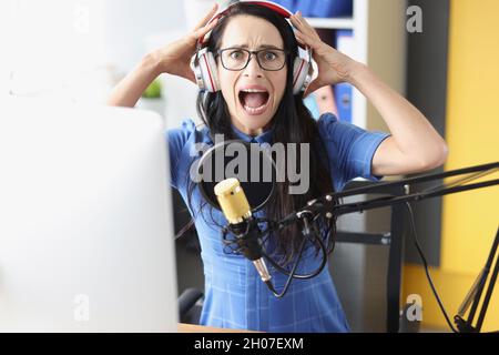 Young woman shouts in headphones in front of microphone Stock Photo