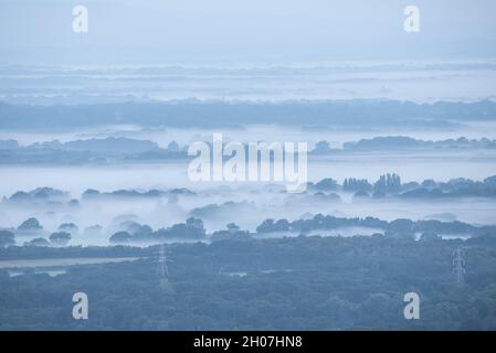 Stunning foggy morning landscape image looking across fields on the South Downs National Park in rolling English contryside during late Summer Stock Photo