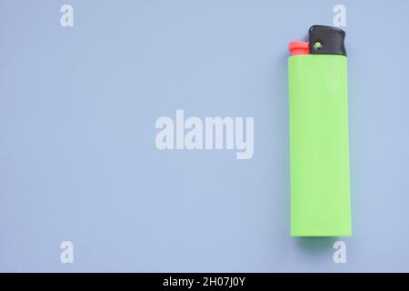 One green lighter on a blue table. Stock Photo