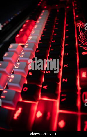 Red Backlit Mechanical Keyboard with black, white, red keycaps at an angle Stock Photo