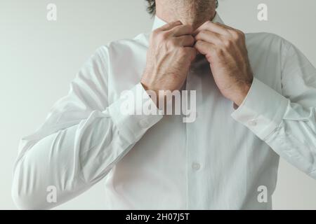 Businessman getting dressed, business person buttoning his white shirt, close up with selective focus Stock Photo