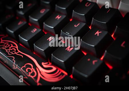 Red Backlit Mechanical Keyboard with black, white, red keycaps at an angle Stock Photo