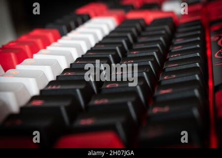 Red Backlit Mechanical Keyboard with black, white, red keycaps at an angle Stock Photo