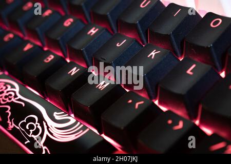 Red Backlit Mechanical Keyboard with black, white, red keycaps at an angle Stock Photo