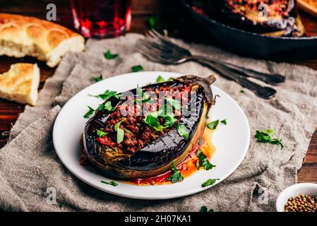 Baked eggplant stuffed with ground beef, tomatoes and spices on white plate. Traditional dish Karniyarik of turkish cuisine Stock Photo