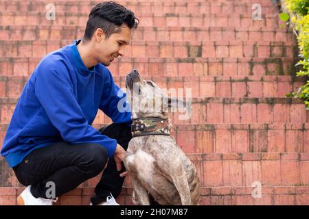 Man looking at his pet and smiling while petting it. Tender dog and its owner. Man dressed in a blue buso bending down to touch his pet on a narnaja Stock Photo