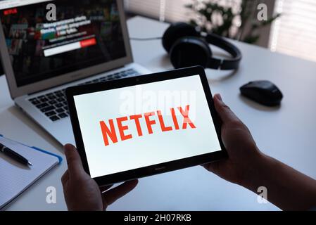 Wroclaw, Poland - JUN 17, 2021: Man with Netflix logo on screen. Netflix is most popular video streaming platform. Stock Photo
