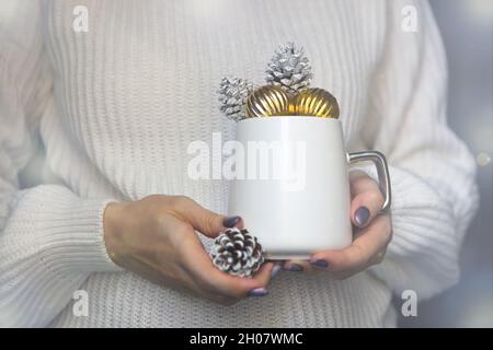 white christmas cup on woman hands with pine cones-winter mug close up for new year time concept Stock Photo