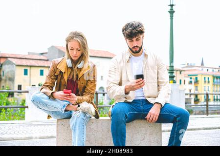 Multicultural group of friends using mobile phones - Students sitting in a row and typing on smartphones Stock Photo