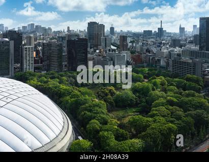 tokyo, japan - may 03 2021: Bird's eye view of the forest of the Koishikawa Korakuen Gardens surrounded by skyscrapers aside the Tokyo Dome stadium ca Stock Photo